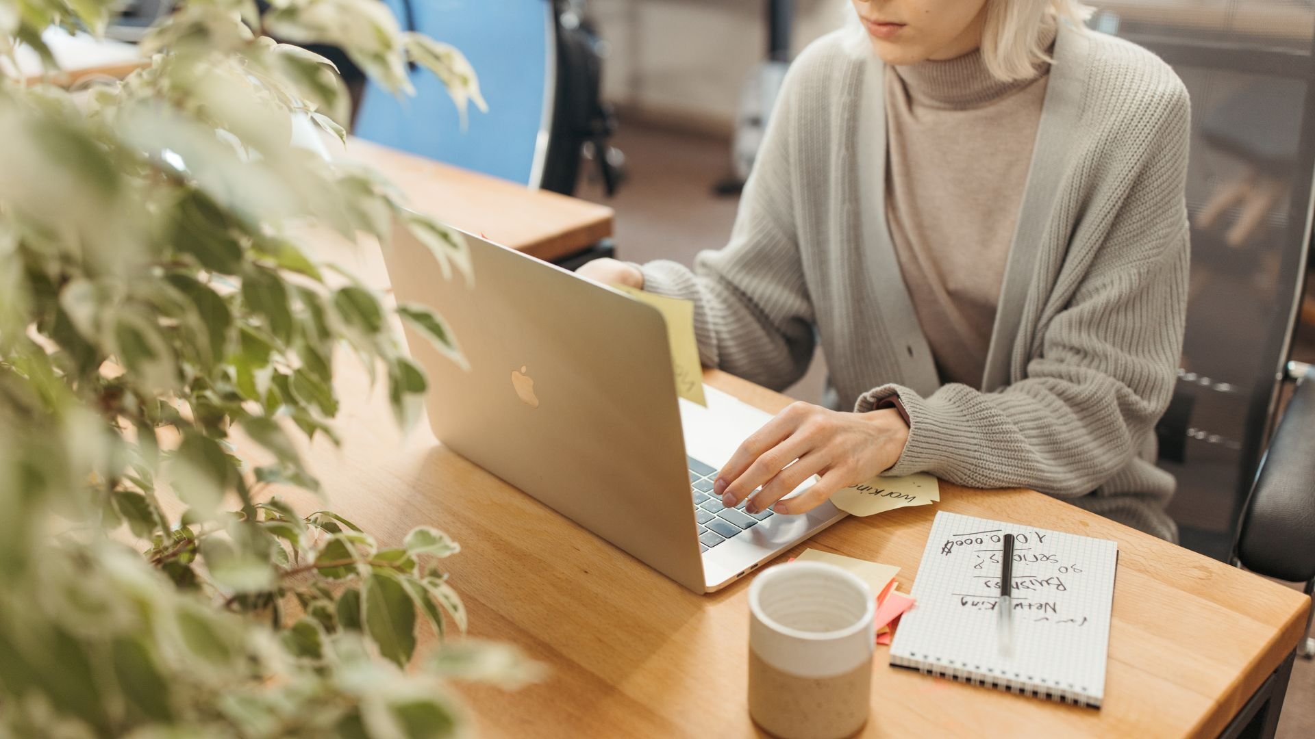a person who works at an email marketing agency sitting at a desk with a laptop and sticky notes