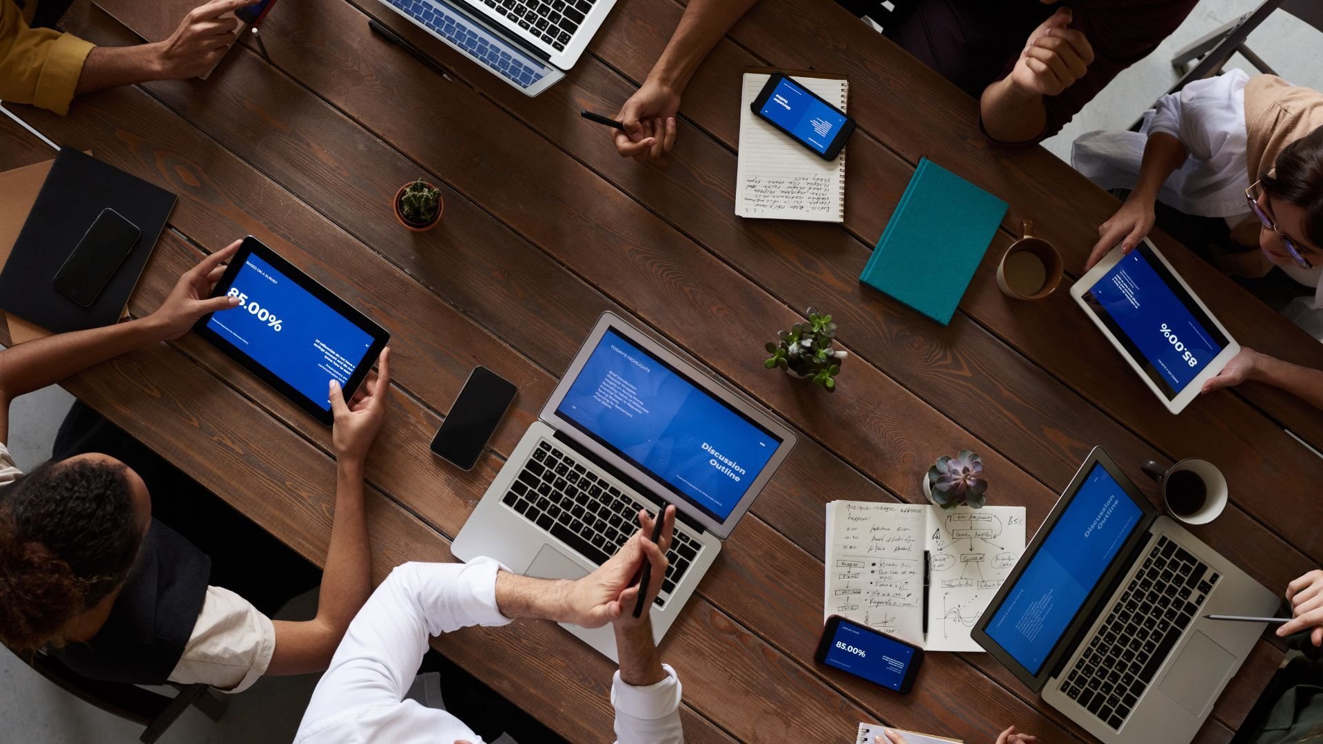 a group of people sitting at a table holding verious devices working on search engine optimization