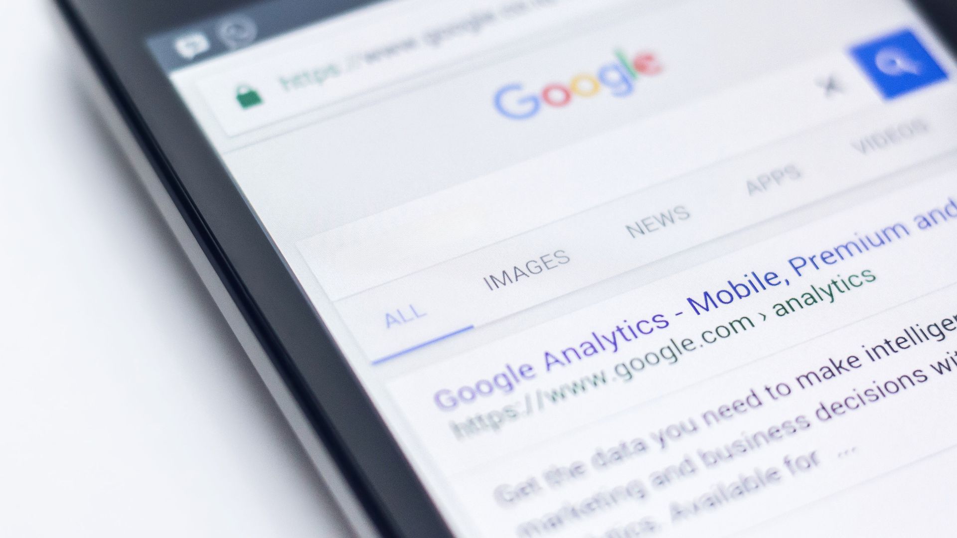 A device laying on a blank surface, open to a search page for Google Analytics